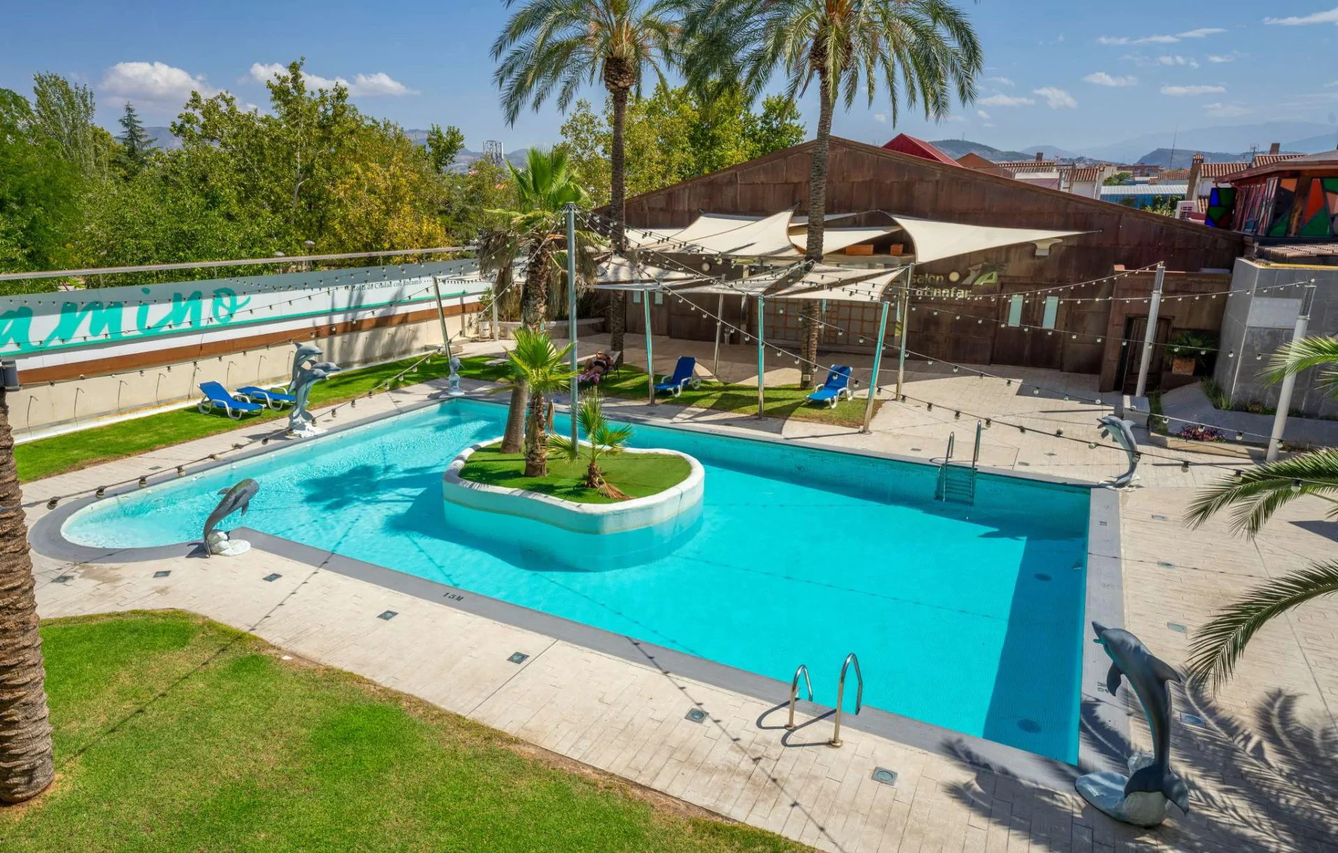 piscina del hotel checkin camino de granada con jardín y zona solarium con hamacas